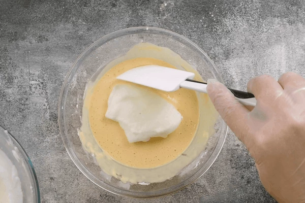 Затем порциями добавить к желтку, аккуратно перемешивая.