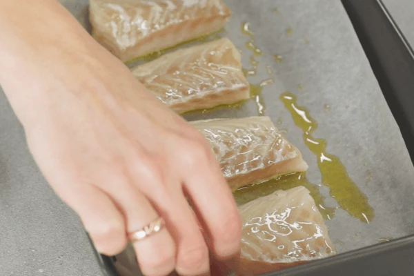 Затем переложить рыбу на противень с пергаментом, смазанный маслом. 