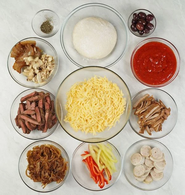 Остывшее мясо нарежьте полосками. Перец очистите от семенной коробки и нарежьте соломкой. Купаты обдайте кипятком и нарежьте кружочками. Сыр натрите на крупной терке. Грибы нарежьте тонкими ломтиками.