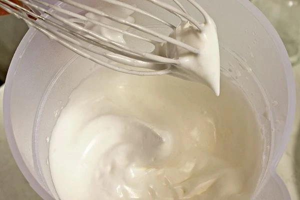 Затем к белкам всыпать  1 стакан сахарной пудры, продолжая взбивать. Влить лимонный сок. Взбивать, пока на поверхности не появится рисунок.