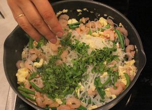 Затем к яйцу добавьте креветки, кинзу, лук, рубленный чеснок,  фасоль,спагетти, подготовленный соус обжарьте 2-3 минуты. Посыпьте арахисом, перемешайте и снимите с огня.