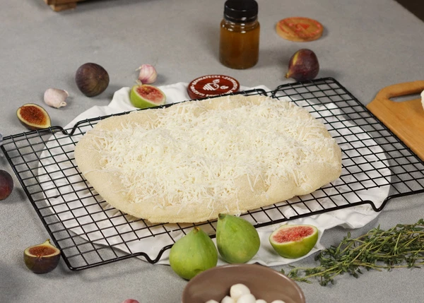 Основу для пиццы разморозить, посыпать тертой моцареллой.