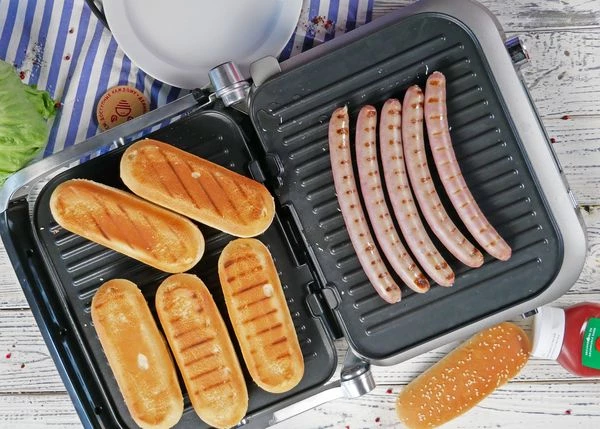 Колбаски и булочки разморозить на нижней полке холодильника. Обжарить с всех сторон на гриле. Колбаски жарить до готовности.