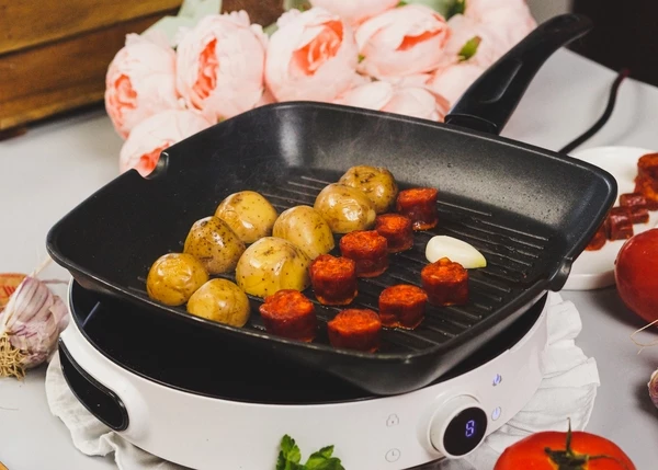 В той же сковороде обжарить в течение 2 минут нарезанный пополам картофель,  кусочки колбасы и зубчик чеснока, посолить. 