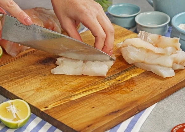 Филе трески разморозить на нижней полке холодильника, нарезать на полоски шириной 2-3 см, посолить.