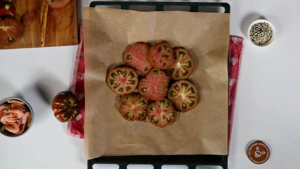 На противень с пергаментом в середину налить оливковое масло и бальзамик. Выложить нарезанные томаты, сформировав круг. Посолить и поперчить. 