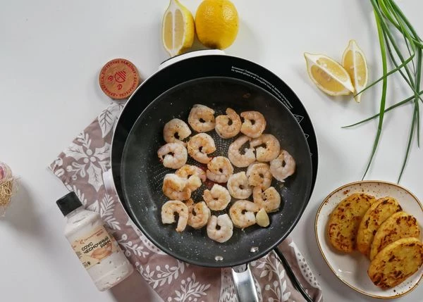 На ту же сковороду добавить оливковое масло,  выложить зубчик чеснока и креветки. Жарить 2 минуты.