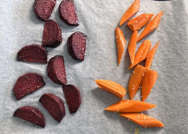 Морковь вымыть, нарезать сегментами, смешать с кунжутом, солью и маслом. На противень рядом со свеклой выложить морковь и запекать еще 30 минут.