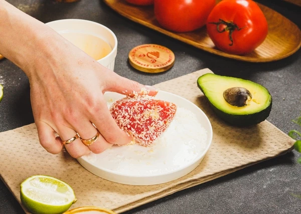 Яйцо посолить, хорошо перемешать. Тунец разморозить на нижней полке холодильника. Обмакнуть в яйцо. Затем запанировать в стружке. 
