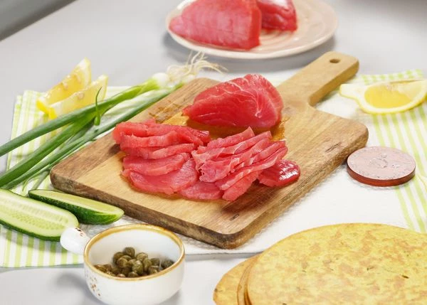 Филе тунца разморозить на нижней полке холодильника. Нарезать слайсами толщиной 1,5-2 мм.