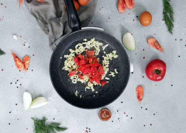 Затем добавить нарезанный кубиком помидор, жарить еще пару минут на среднем огне. Посолить и поперчить.