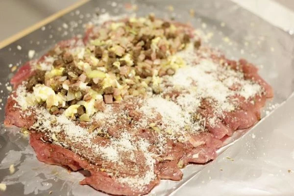 На рабочей поверхности расстелить фольгу, смазать оливковым маслом, в центр выложить мясо индейки в виде прямоугольника. Посыпать тертым чесноком и сыром.