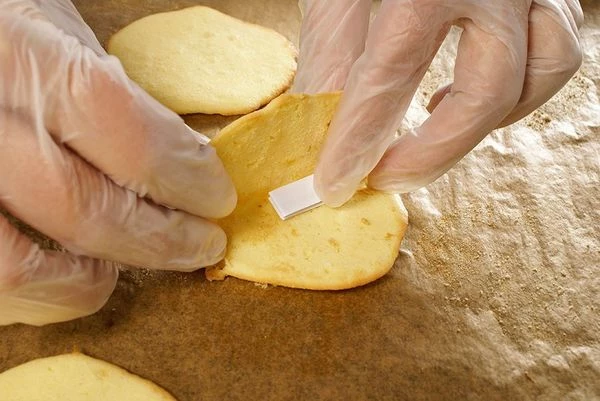 Быстро снять готовые кружки с противня, пока горячие. Положить внутрь записку с пожеланием, свернуть пополам, потом еще раз пополам.