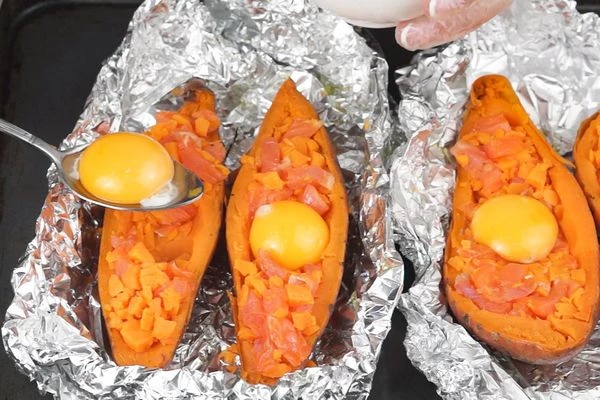  Получившейся начинкой зафаршировать наши "лодочки", оставив в центре небольшое углубление. В центр каждой половинки выложить желтки, поставить в разогретую духовку еще на 5 минут. Готовый батат украсить мелко нарезанной зеленью.