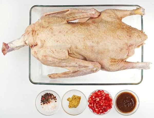 Гуся разморозить естественным способом на нижней полке холодильника. Удалить остатки перьев (если необходимо). Для маринада смешать оливковое масло с бальзамическим уксусом, добавить горчицу. Затем тушку натереть солью и перцем внутри и снаружи.  Зерна граната размять ложкой или пестиком. Обмазать гуся гранатом и заправкой. Закрыть пищевой пленкой и убрать в холодильник мариноваться на 2 суток.