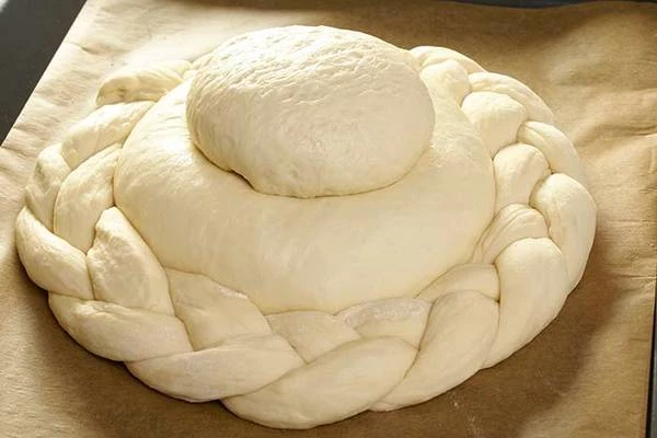 Из третей части теста сделать еще один колобок с начинкой из грибов.  Выложить на застеленный пергаментом противень большой колобок с начинкой, на него сверху колобок по меньше, вокруг выложить косичку.