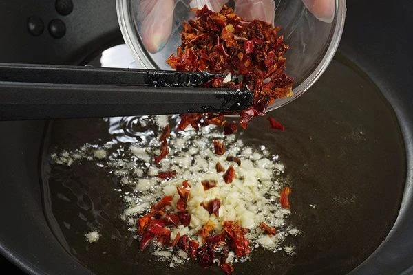 На разогретой с оливковым маслом сковороде обжарить мелко нарезанный чеснок и красный перец.