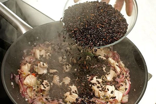 Всыпать к курице и овощам сырой черный рис, прокалить.