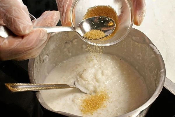 Добавить кокосовую стружку и коричневый сахар, перемешать. Снять с огня и дать еще рису постоять под крышкой 10-15 минут.