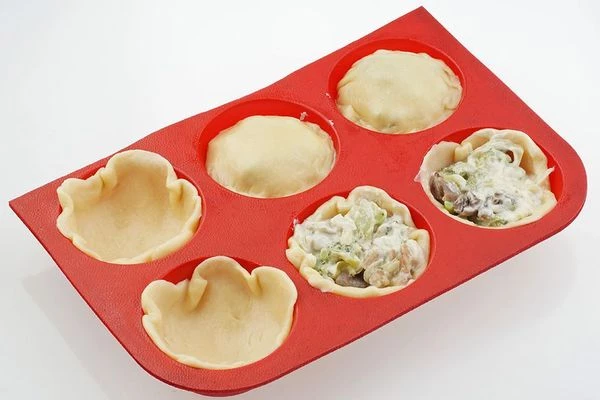 Тесто раскатать толщиной примерно 3-4мм. Вырезать сначала кружки большего диаметра, уложить в форму. Затем выложить начинку. Закрыть кружками меньшего диаметра и защипнуть по краям. Смазать яйцом.