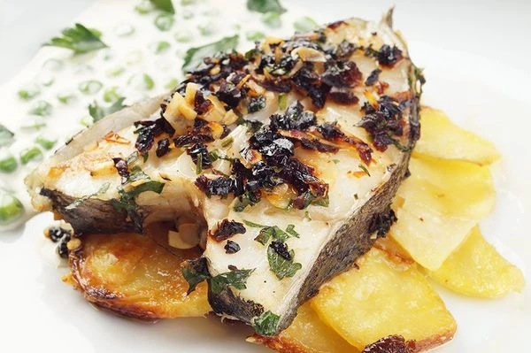 На тарелку выложить мильфей из картофеля, сверху стейк палтуса. Украсить зеленью и соусом.