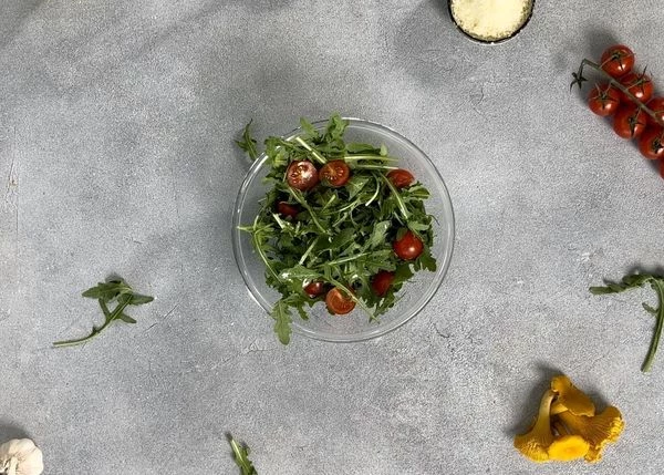 Рукколу смешать с соусом, добавить помидоры черри.