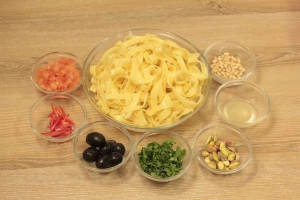 Отварить пасту в течение 8 минут в большом количестве воды (1:10). Сбрызнуть оливковым маслом, остудить. Перец чили нарезать тонкой соломкой, чеснок мелко порубить. С моркови и цукини, с помощью овощерезки, нарезать тонкие пластинки.