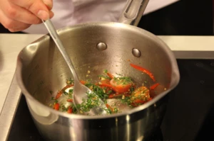 В разогретый сотейник с оливковым маслом добавить тертый чеснок, мелко нарезанный перец чили, порубленную зелень, помидоры черри, разрезанные на половинки, размоченные вяленые томаты, соль.