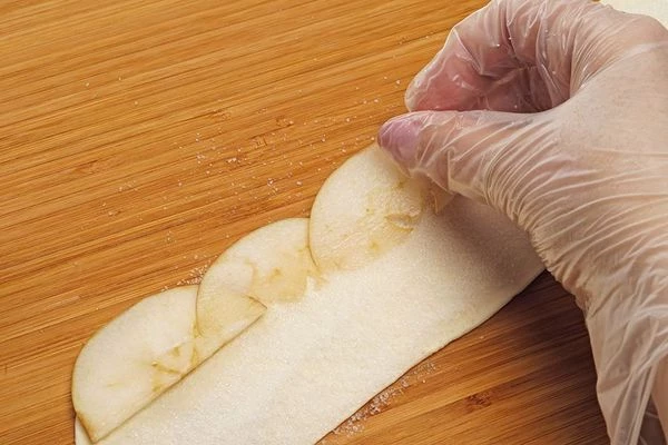 С одного края полоски из теста выложить яблоки.