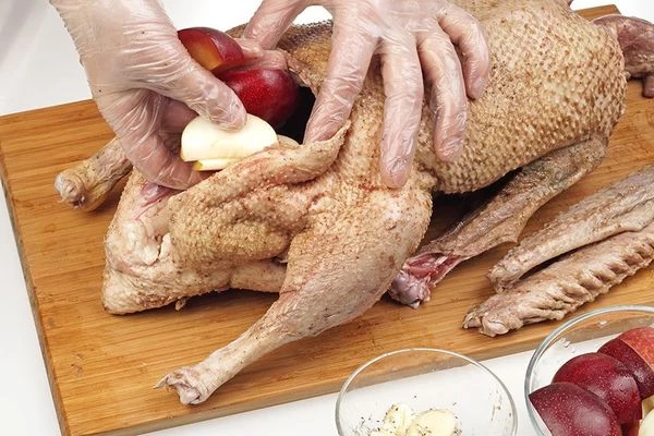  Наполните гуся яблоками, сливами, дольками чеснока, перемешанными с солью и перцем.