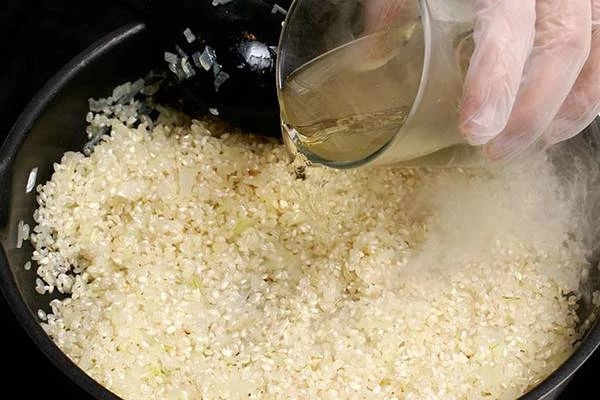 Влить белое вино, дать выпариться, постоянно помешивая.