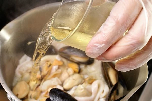 Влить в морепродукты белое вино и дать немного ему выпариться.