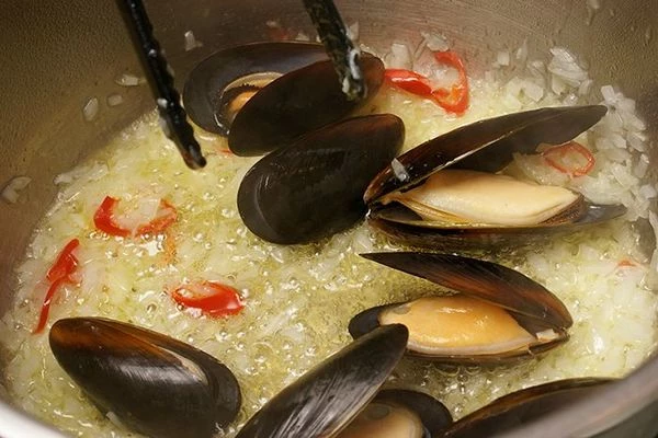 Добавить перец чили и мидии, посолить, поперчить, жарить 1-2 минуты.