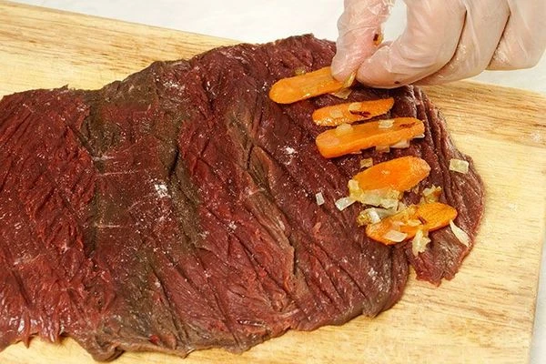 На пласт оленины с краю  выложить обжаренные овощи.