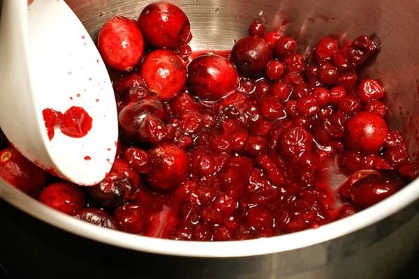 В кастрюле смешать бруснику и клюкву, слегка раздавить ягоды пластиковой ложкой или пестиком.