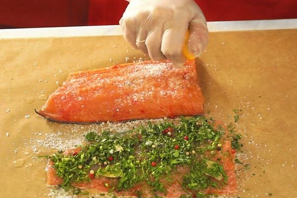 Натереть филе сверху смесью соли и перца, выложить разломанный на несколько частей лавровый лист, посыпать смесью перцев и рубленной зеленью. Второе филе также натереть солью и сахаром, полить соком лимона. 