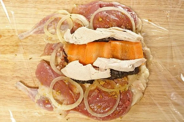 С двух сторон от морковного рулетика выложить чернослив и ломтики куриного филе