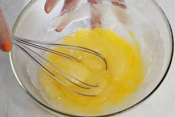 Приготовить тесто: взбить в глубокой миске сахар и яйца в пену, влить растопленное сливочное масло. Еще раз взбить.