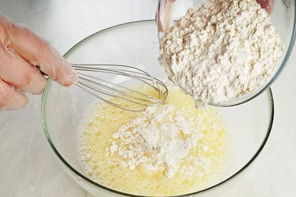 Затем добавить просеянную муку. Хорошо перемешать до однородной консистенции жидкой сметаны.