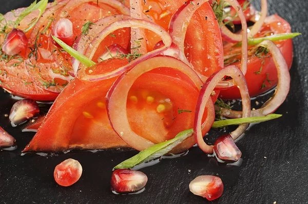 Помидоры нарезать крупными дольками, посолить, поперчить 
по вкусу. Затем перемешать с луковой смесью. Выложить на тарелку, посыпать зернами граната и полить оливковым маслом. Украсить зеленым луком и перцем чили.
