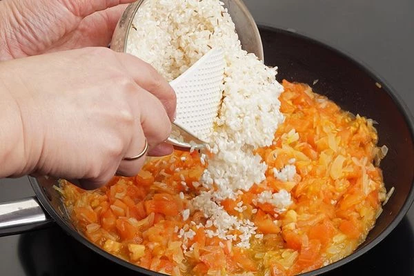 К обжаренным овощам добавить промытый рис, кукурузную муку,  тушить 5-7 минут.