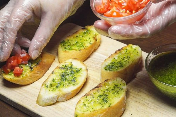 Обжаренный багет смазать соусом песто, сверху выложить нарезанный помидор (конкасе).