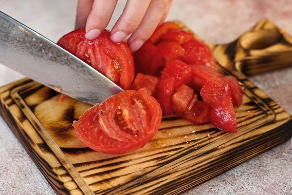 Томаты вымыть, надрезать у плодоножки и ошпарить их кипятком. Снять кожицу. Нарезать кубиком.