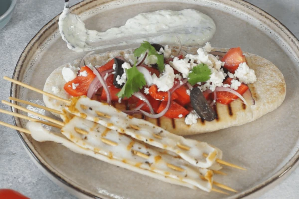 Рядом выложить шашлычки из кальмаров. Оформить веточками кинзы. Подавать с соусом. Приятного аппетита!