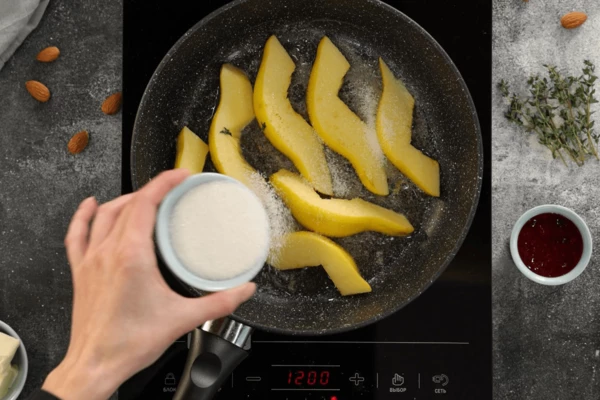 В качестве гарнира приготовить карамелизированную айву. Для этого в нагретую сковороду выложить сливочное масло, затем оставшиеся дольки айвы, обжарить пару минут, всыпать сахар, готовить на низком нагреве, пока сахар не карамелизуется, а айва не станет мягкой. Выключить нагрев.