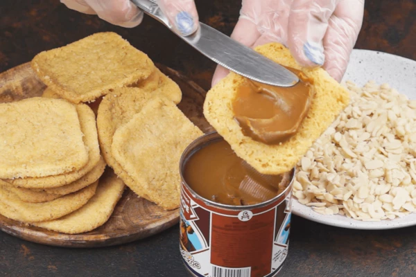 Готовое печенье охладить до комнатной температуры. Одну половинку печенья смазать вареной сгущенкой, накрыть вторым.