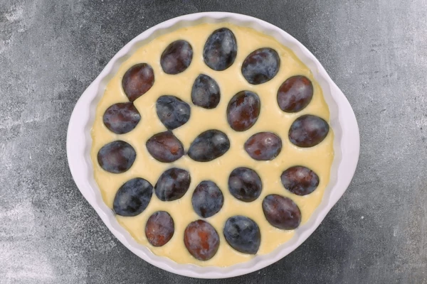 Из сливы удалить косточки и выложить по всей поверхности на тесто.