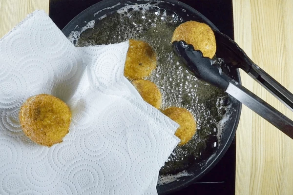 Выложить колобки на бумажное полотенце, чтобы удалить излишки масла.
