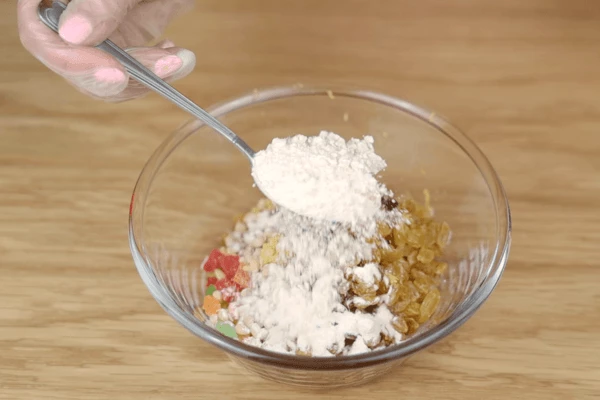 В чашке смешать цукаты, орехи, изюм, цедру  одного лимона, добавить 1-2 ст.л ложки муки и перемешать.