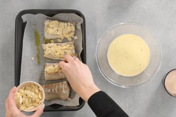 Посыпать треску миндальными лепестками. 